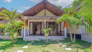 A resort with thatched-roof buildings, palm trees, and a well-maintained lawn. - Kalpataru Cottage (Bali)