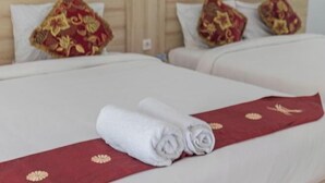 A hotel room with two beds, each with a red bedspread and matching pillows. - Kalpataru Cottage (Bali)