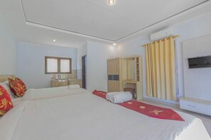 A hotel room with a bed, a wardrobe, a TV, and a window with curtains. - Kalpataru Cottage (Bali)