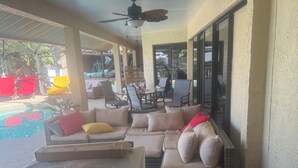 A covered outdoor seating area with a pool, cushioned sofas, and a ceiling fan. - 3 bedroom Amazing cool house with tons of character! (Port Charlotte)
