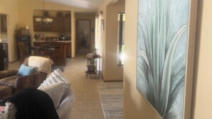 A living room with a sofa, a painting, and a kitchen in the background. - 3 bedroom Amazing cool house with tons of character! (Port Charlotte)
