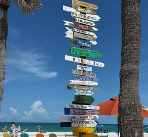Um sinal vertical com placas indicando direções para várias cidades e distâncias.