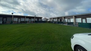 A building with a flat roof, large windows, and a grassy area in front.