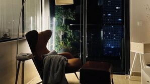 Una sala de estar moderna con un ventanal grande, una lámpara de pie, una butaca y una mesita.