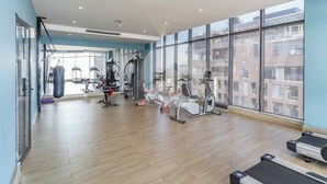 Un gimnasio espacioso con diversos equipos de ejercicio, amplias ventanas y un diseño de interiores moderno.