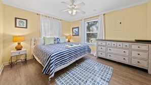 A bedroom with a bed, nightstand, dresser, and a ceiling fan. - Bay Leave | Perfect coastal getaway! (Gulf Shores)