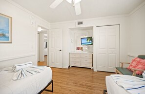 A hotel room with a bed, a desk, a chair, a TV, and a wardrobe. - Beachside Comfort – 2BR Retreat with Pool (Fort Myers Beach)