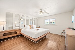 Ein Schlafzimmer mit einem Bett, einem Deckenventilator, einem Fenster und einem Schreibtisch.