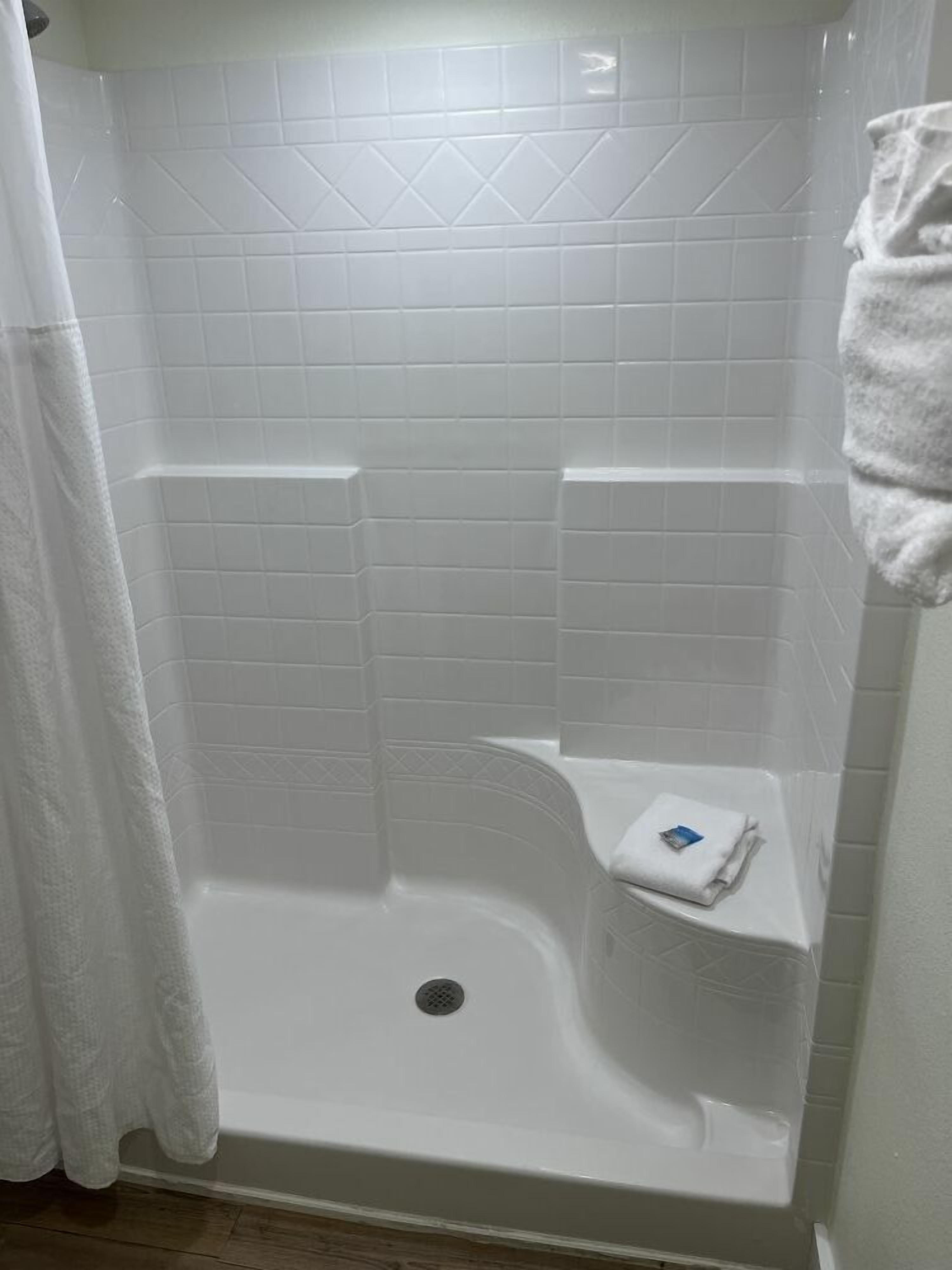 A white shower with a built-in shelf and a towel rack.
