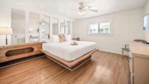 Ein Schlafzimmer mit einem Bett, einem Deckenventilator, einem Fenster und einem Schreibtisch.