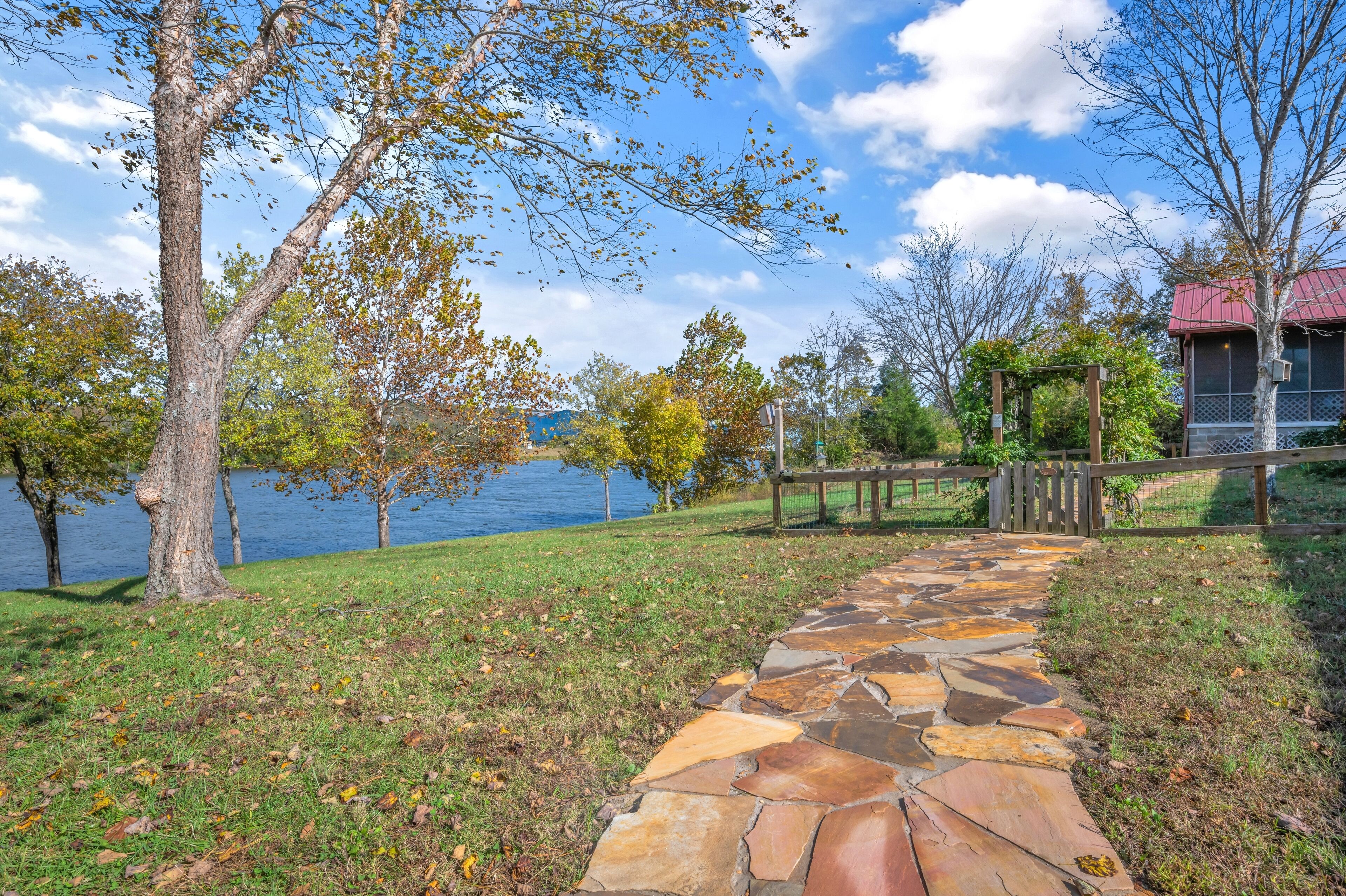 A stone pathway leading to a gazebo by a lake.