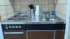 Een kleine keuken met houten kastjes, een roestvrijstalen spoelbak en een ingebouwd fornuis.