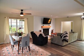 Ein Wohnzimmer mit Kamin, Deckenventilator, Wand-Fernseher und einer Couch.