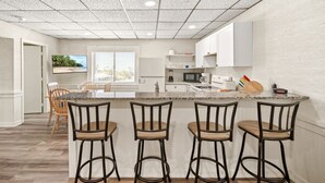 Une cuisine moderne dotée d’un îlot central, de tabourets de bar et offrant une vue sur l’extérieur.