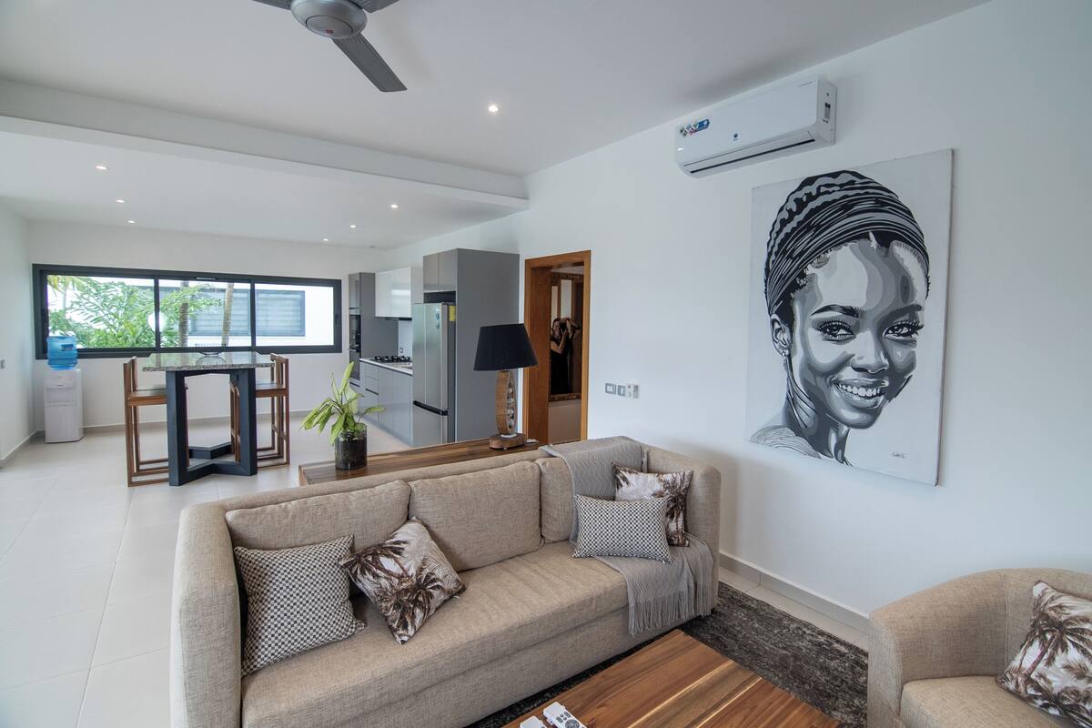 Una sala de estar moderna con un sofá color beige, una mesa de centro y un ventanal grande.