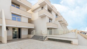 Un edificio residencial de varios pisos con una escalera central, un espacio exterior cubierto y una entrada visible.