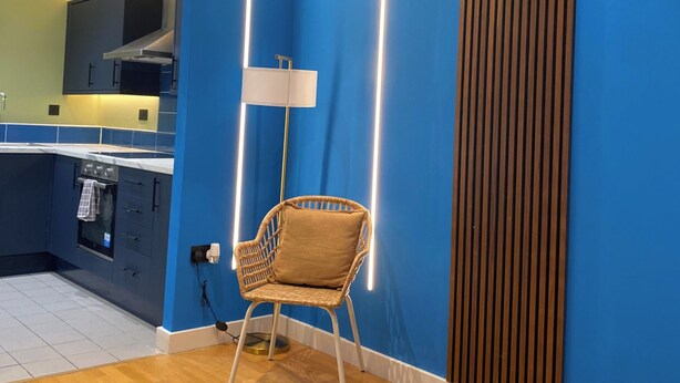 Une cuisine moderne avec des murs bleus, un plancher en bois et une chaise en osier.