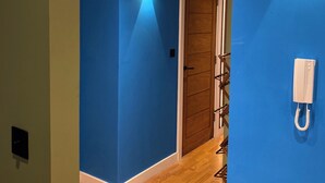 Un couloir aux murs bleus, doté d’un plancher en bois, d’une porte en bois et d’un téléphone blanc fixé au mur.