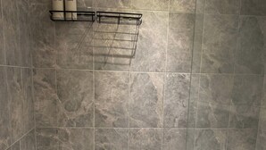 Une salle de bain équipée d’une baignoire, d’un lavabo et d’une étagère où sont rangés les articles de toilette.