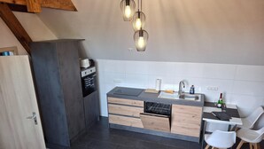 A modern kitchen with a built-in oven, dishwasher, and a dining area with two chairs. - Appartement mit Dachterrasse, Monkebude (Monkebude)