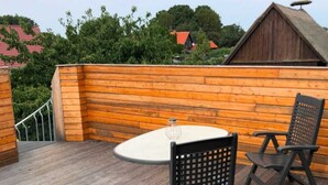A wooden deck with a round table and two chairs, surrounded by a wooden fence. - Appartement mit Dachterrasse, Monkebude (Monkebude)