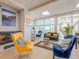 A modern interior with a fireplace, seating area, and large windows.