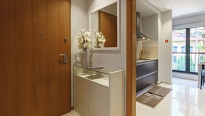 A modern bathroom with a wooden door, a glass sink, a mirror, and a vase with white flowers. - MAR E SOL: The ultimate Madeira escape with stunning views and modern comforts! (Funchal)