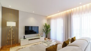 A modern living room with a flat-screen TV, a glass coffee table, a sofa, and a potted plant. - MAR E SOL: The ultimate Madeira escape with stunning views and modern comforts! (Funchal)