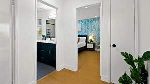 Une chambre d’hôtel avec une salle de bain, un lit, une table de chevet et une plante.