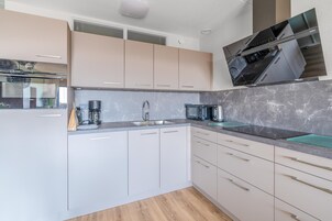 Una cocina moderna con armarios blancos, encimera de mármol y electrodomésticos de acero inoxidable.