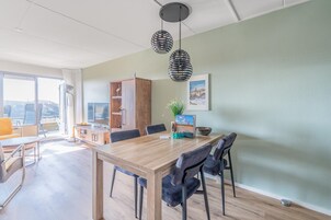 Un comedor moderno con una mesa de madera, sillas negras y lámparas colgantes.