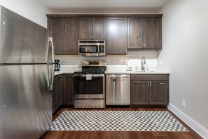 A compact kitchen with stainless steel appliances, wooden cabinets, and a checkered rug. - The Alpine Getaway - Mtn View, Dog Considered* (Crested Butte)