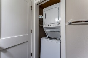 A laundry room with a washer and dryer, a door, and a shelf with folded clothes. - The Alpine Getaway - Mtn View, Dog Considered* (Crested Butte)