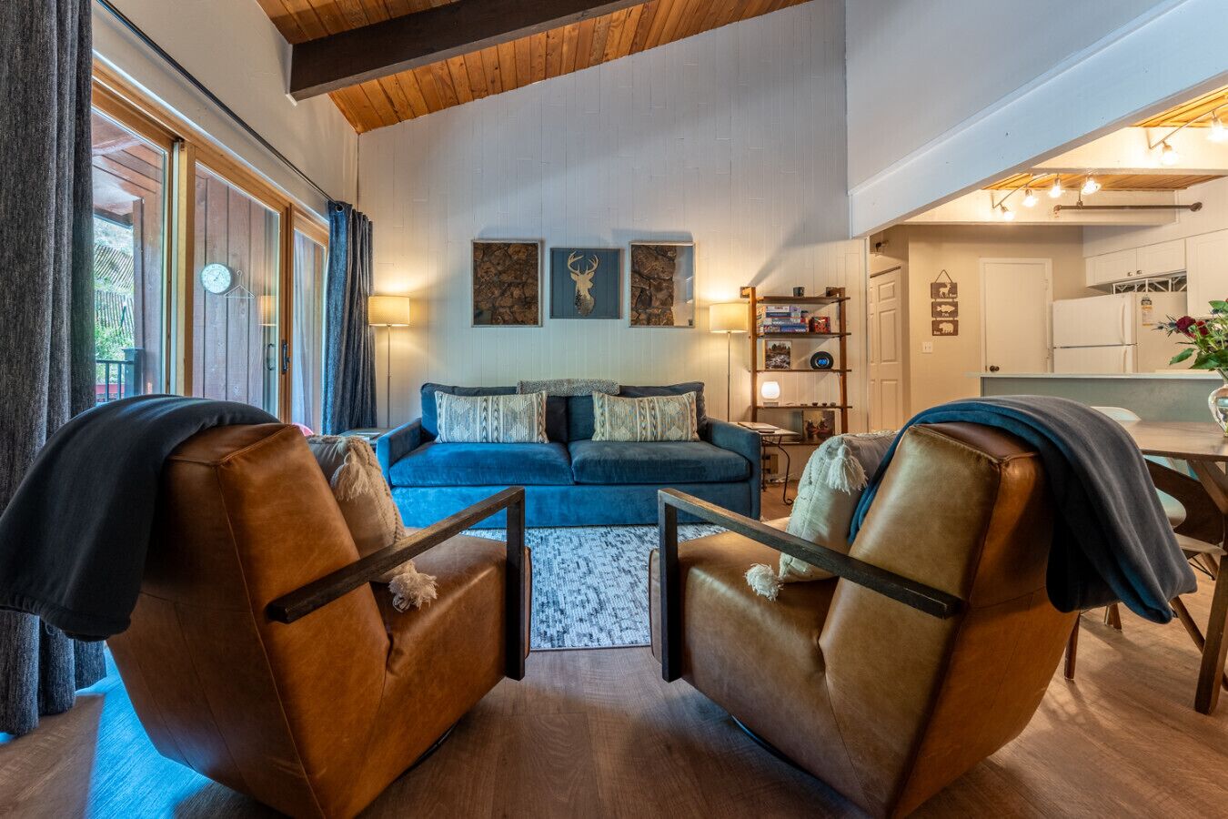 A cozy living room with a blue sofa, two leather armchairs, a wooden coffee table, and a stone accent wall.