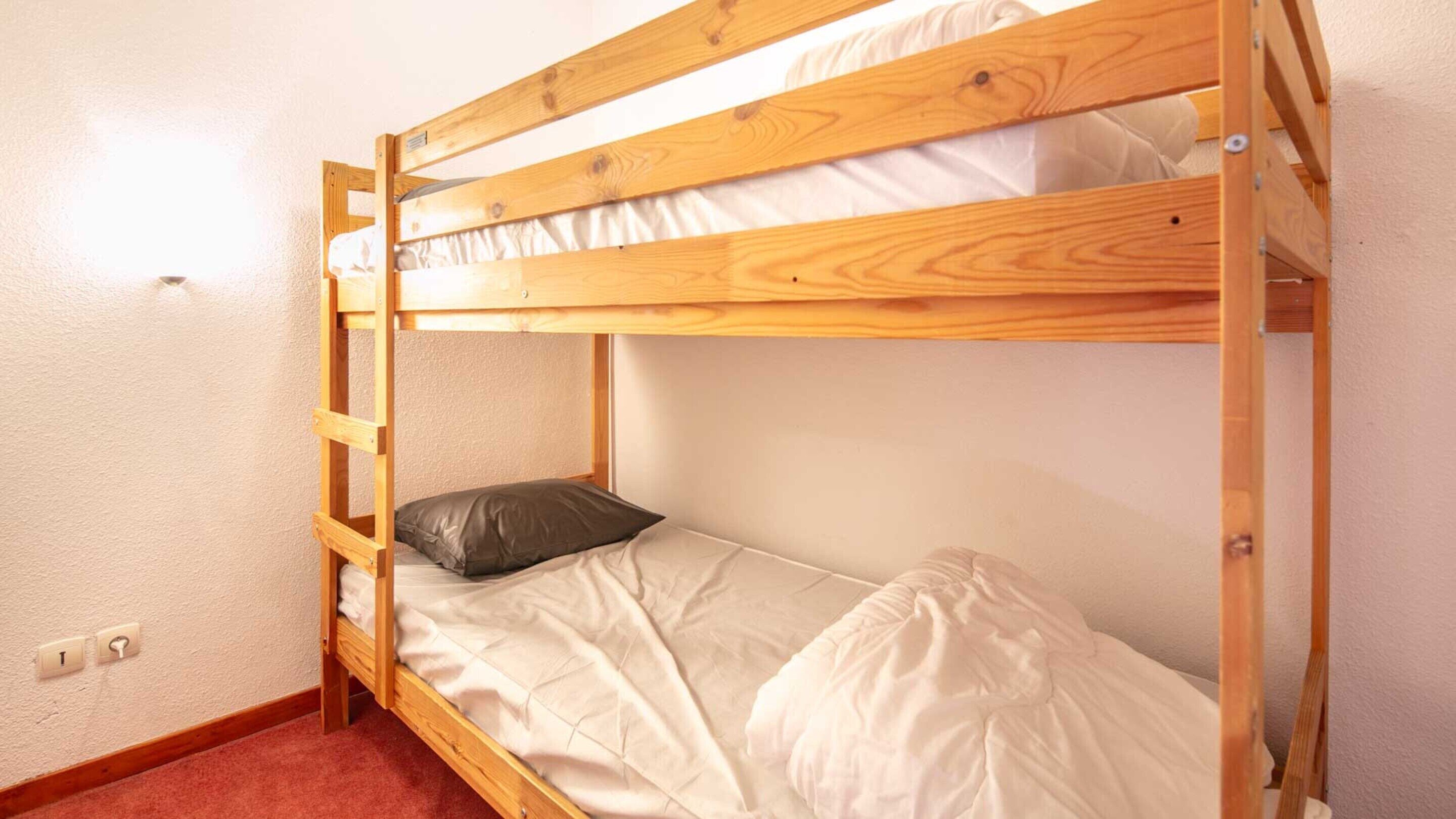 A bunk bed with a ladder, a pillow, and a mattress.