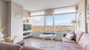 A living room with a large window, a sofa, a coffee table, and a TV. - 4-person Apartment With Island View (De Koog)