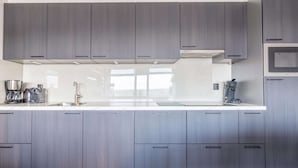A modern kitchen with grey cabinets, a white countertop, and stainless steel appliances. - 4-person Apartment With Island View (De Koog)