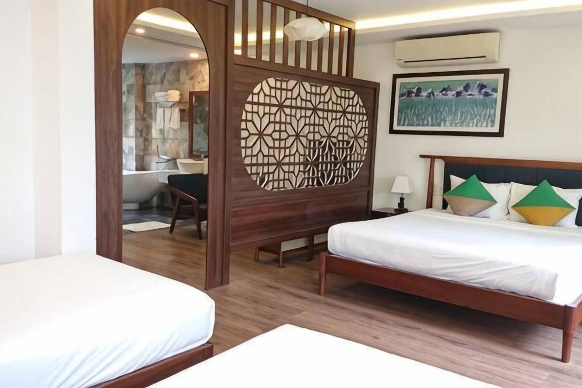 A hotel room with a bed, a desk, and a shower area.