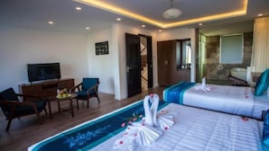 Une chambre d’hôtel avec deux lits, un bureau avec une chaise, une télévision et une salle de bain visible à travers une porte ouverte.