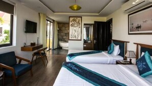 Une chambre d’hôtel avec deux lits, une télévision, un bureau et une vue sur l’extérieur.