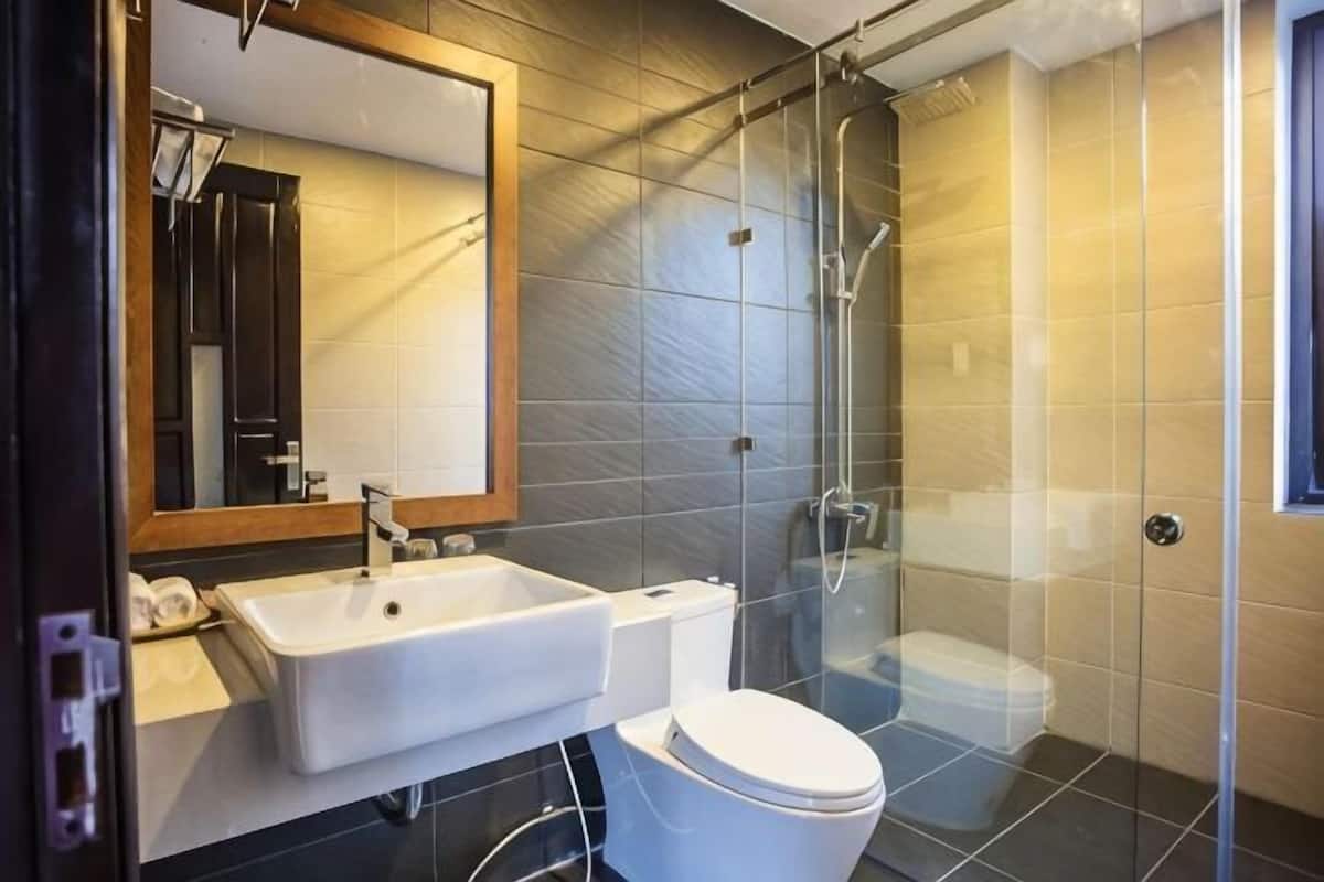 A modern bathroom with a glass shower enclosure, a white sink, and a toilet.
