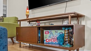 Een houten entertainmentkast met een lavalampe, een spelbord en een kleine beeldje.