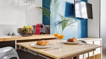 Desayuno con cruasanes, jugo de naranja y una cesta de frutas sobre una mesa de madera.