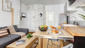 A modern living room with a grey sofa, a wooden coffee table, and a dining area with a wooden table and chairs. - Cozy 1BR in Montorgueil (Paris)