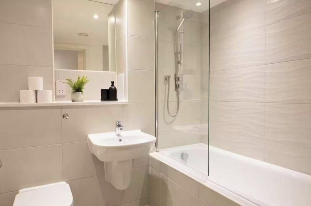 Un baño moderno con ducha acristalada, lavamanos blanco y bañera.