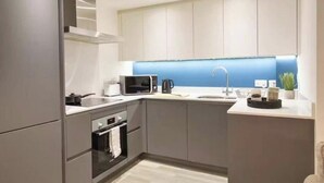 Une cuisine moderne avec des meubles gris, un four à micro-ondes, une bouilloire et un évier.