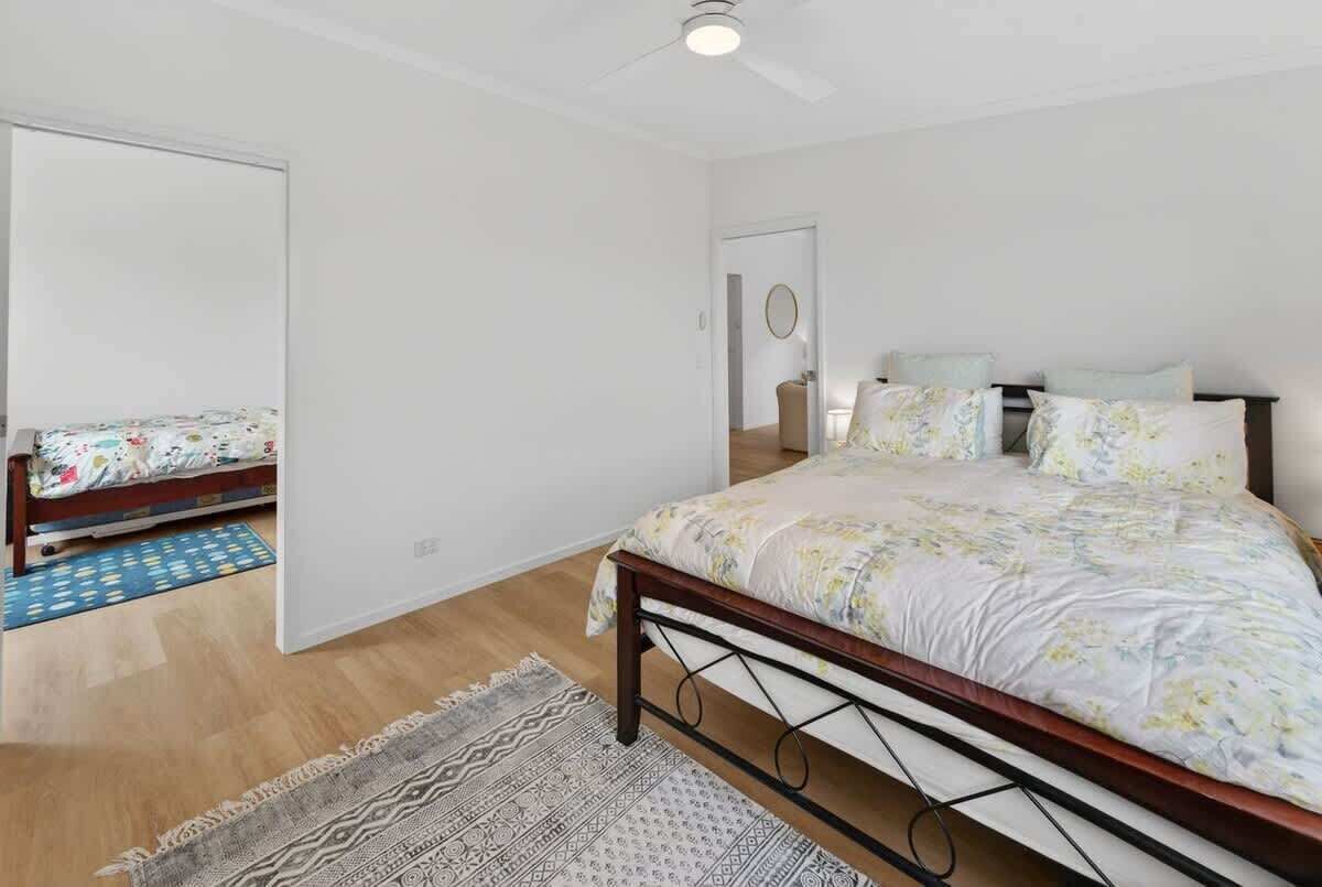 A bedroom with a bed, a mirror, a door, and a patterned rug.