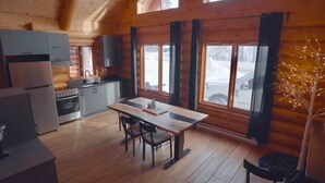 Eine gemütliche Landhausküche mit Holzwänden, einem Esstisch und einem Kühlschrank.