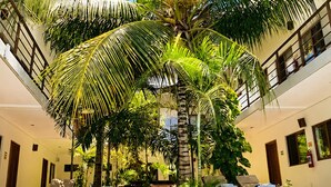 A poolside area with a palm tree, lounge chairs, and a clear blue pool. - Hotel Centrico Tulum (Tulum)