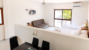 A modern hotel room with a balcony, a dining area, and a TV. - Hotel Centrico Tulum (Tulum)